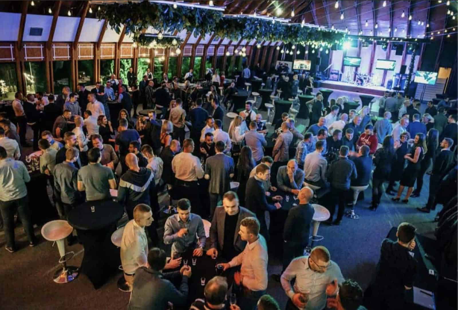 Poslovni event s gostima, barskim stolovima i pozornicom